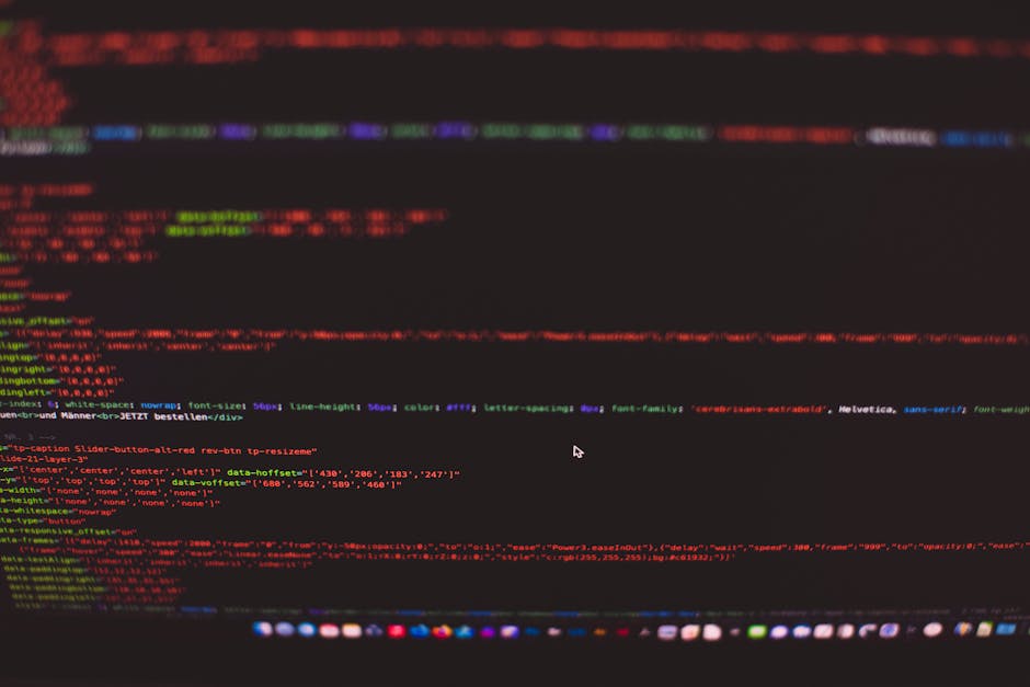 A close-up photograph of a computer screen displaying lines of computer code in multiple colors including red, green, blue, and purple, set against a dark background. The code appears to be part of a 