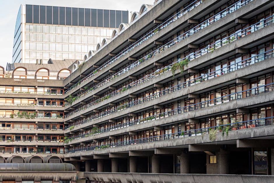 A multi-storey residential building with outdoor balconies featuring various potted plants and greenery, including small shrubs and flowering plants. The building's concrete structure shows horizontal